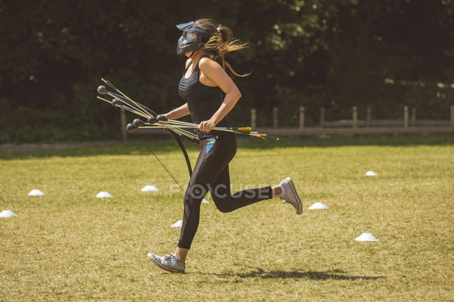 Donna che corre mentre si allena nel campo di addestramento in una giornata di sole — Foto stock