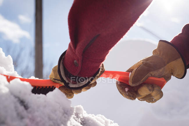 Крупный план человека, убирающего снег с автомобиля зимой — стоковое фото