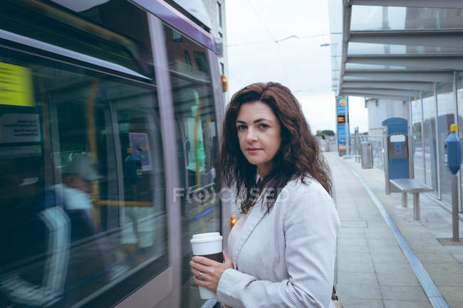 Portrait of businessman with coffee cup standing at railway station — Stock Photo