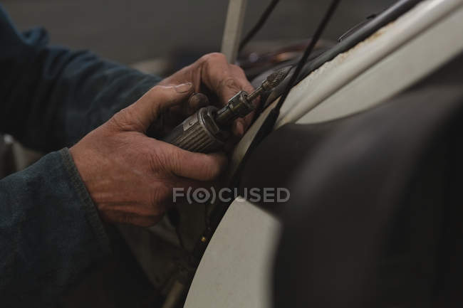 Mecânico masculino usando mini máquina de broca na garagem — Fotografia de Stock