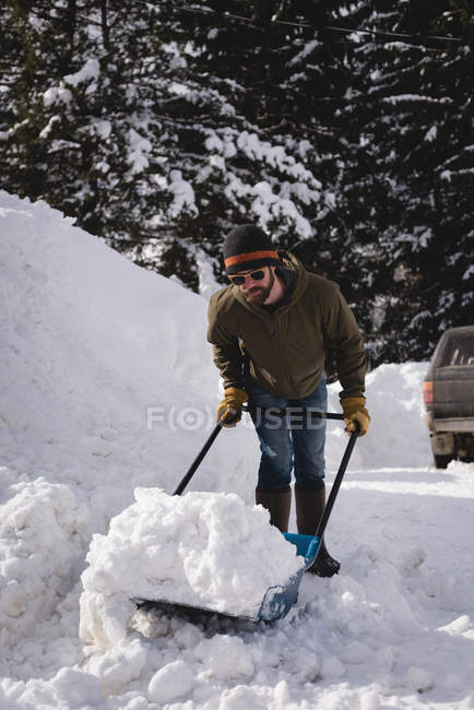 Hombre limpiando nieve con empujador de nieve durante el invierno - foto de stock