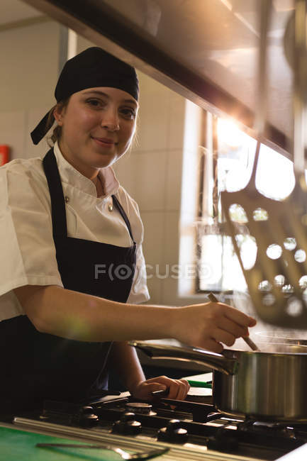 Chef fêmea degustação de alimentos na cozinha no restaurante — Fotografia de Stock