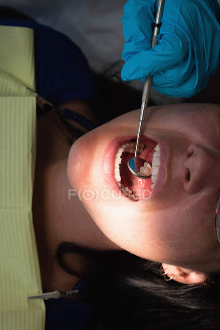 Крупный план стоматолога-мужчины, осматривающего пациентку в клинике — стоковое фото
