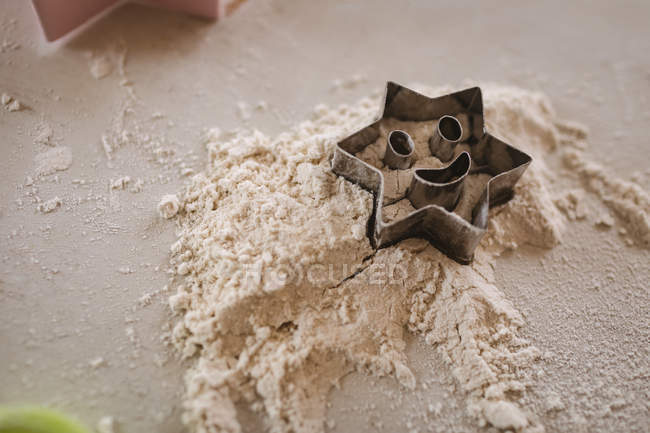 Primer plano del cortador de galletas en forma de estrella en la harina - foto de stock