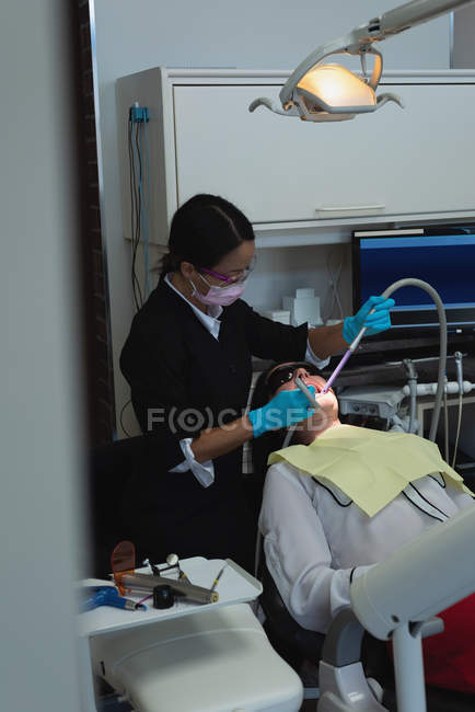 Odontoiatra che esamina una paziente con strumenti in clinica dentale — Foto stock