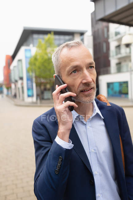 Primer plano del hombre de negocios hablando por teléfono móvil en la ciudad - foto de stock
