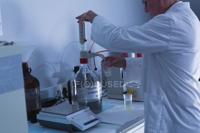 Вид сбоку ученого-мужчины, экспериментирующего в лаборатории — стоковое фото
