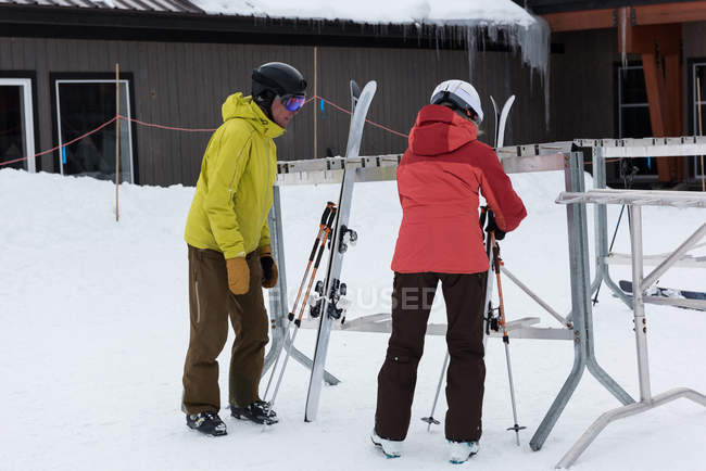 Senior couple arranging ski board on rack in snowy landscape — Stock Photo