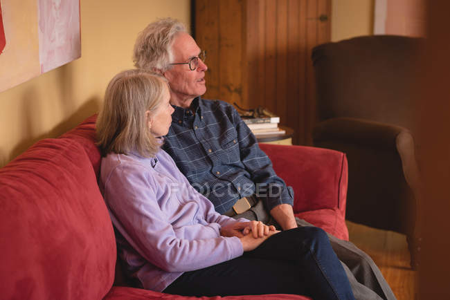 Couple sitting together on sofa in living room at home — Stock Photo