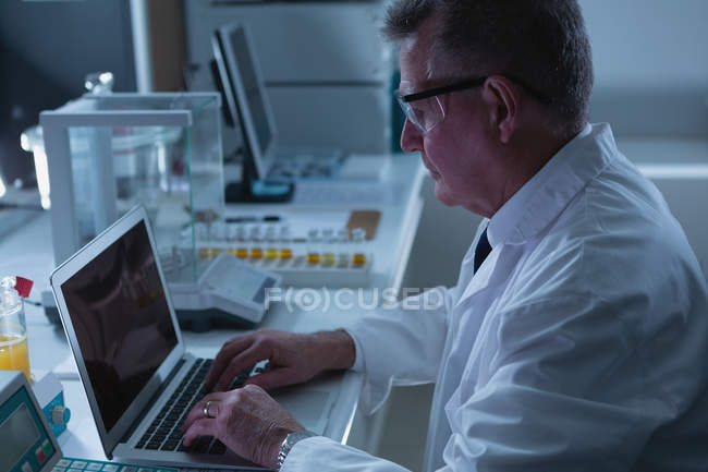 Вид збоку чоловіка-вченого, що використовує ноутбук у лабораторії — стокове фото