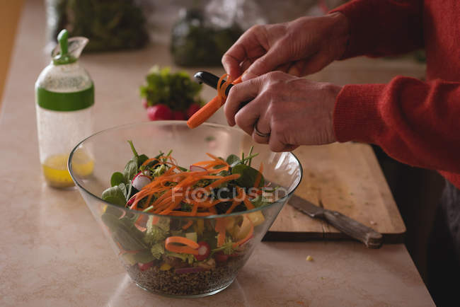 Senior man preparing salad in kitchen at home — Stock Photo