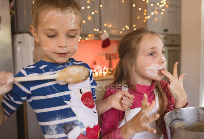 Close-up of siblings tasting the cookie batter in the kitchen — Stock Photo