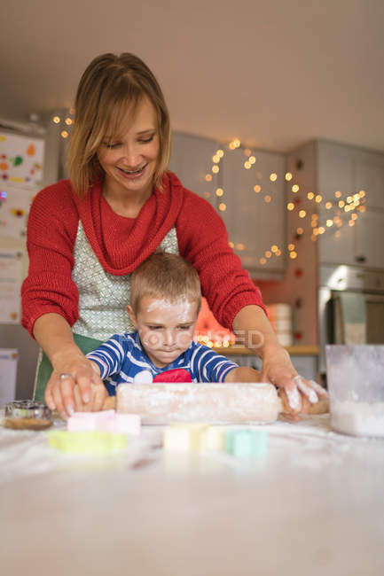 Mother and son rolling the batter for cookies in the kitchen — Stock Photo