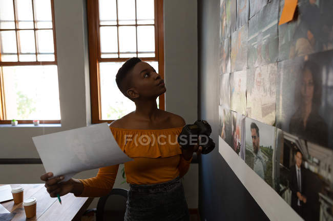 Female executive looking at photos in wall at office — Stock Photo
