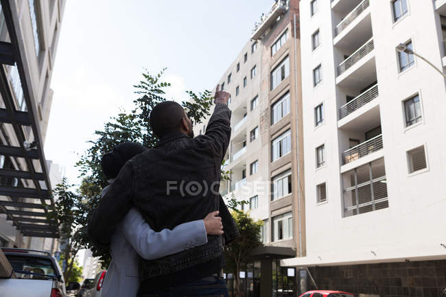 Вид сзади на пару, стоящую с рукой на городской улице — стоковое фото