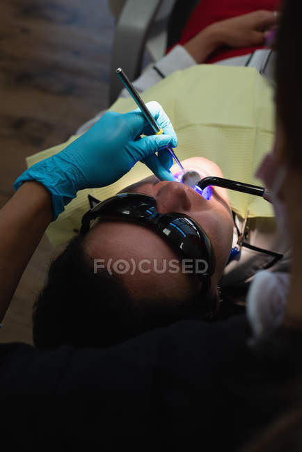 Dentista feminina examinando um paciente com ferramentas na clínica odontológica — Fotografia de Stock