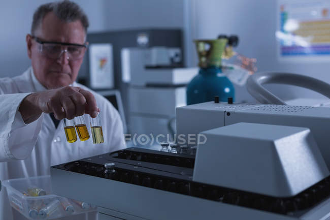 Чоловік-вчений розміщує хімічну пляшку на машині в лабораторії — стокове фото