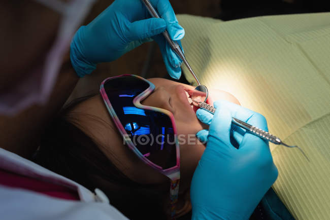 Une dentiste examine un patient avec des outils dans une clinique dentaire — Photo de stock