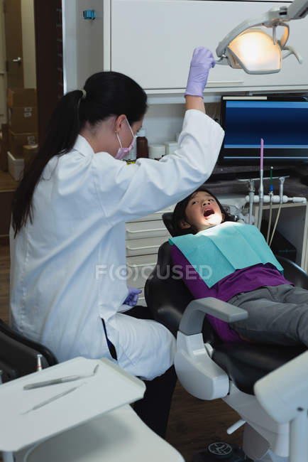 Odontóloga y enfermera examinando paciente en clínica - foto de stock