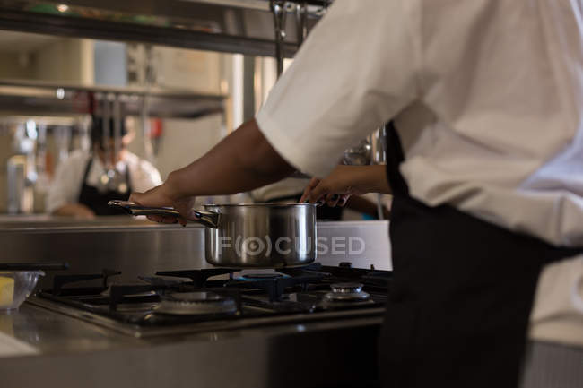Female chef preparing food in kitchen at restaurant — Stock Photo