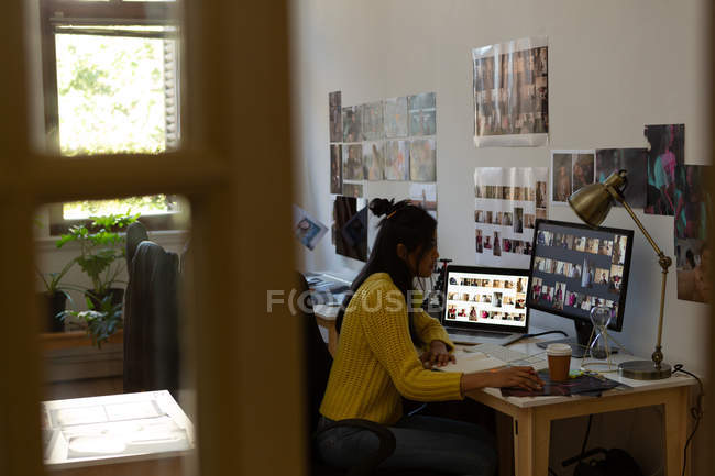 Beautiful female executive listening music in office with legs on table — Stock Photo