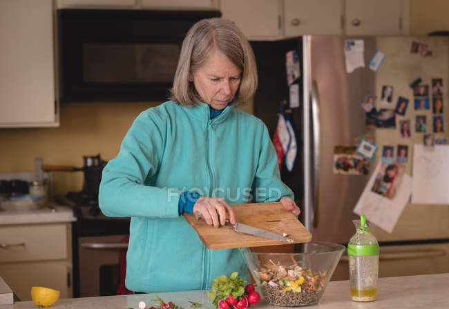 Старша жінка готує салат на кухні вдома — стокове фото