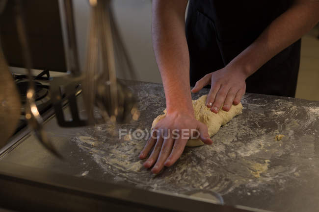 Mid section of chef kneading dough in kitchen at restaurant — Stock Photo