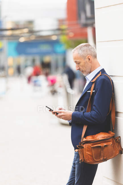 Вид збоку бізнесмена, що використовує мобільний телефон у місті — стокове фото
