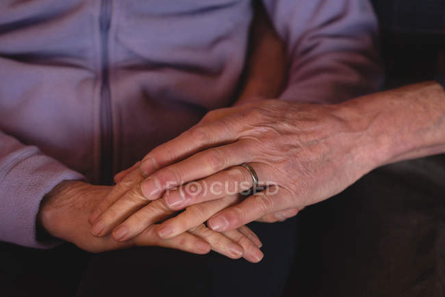 Крупный план пожилой пары, держащейся за руки дома — стоковое фото