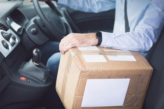 Close-up of delivery man with package driving a delivery van — Stock Photo