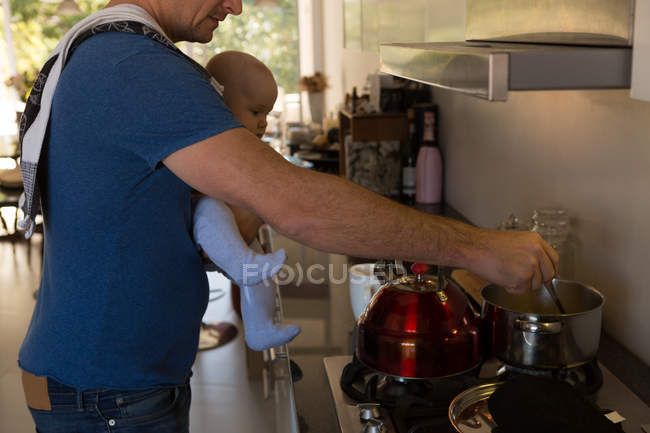 Padre y bebé niño preparando leche en la cocina en casa - foto de stock