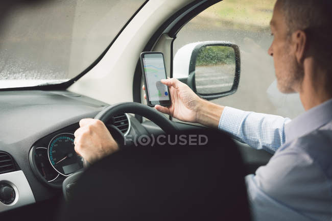 Vista lateral do homem de entrega usando telefone celular enquanto dirige uma van de entrega — Fotografia de Stock