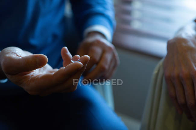 Оптометрист держит контактные линзы на пальце в клинике — стоковое фото