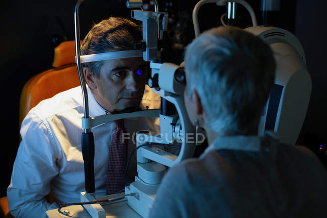 Optometrista examinando os olhos do paciente com lâmpada de fenda na clínica — Fotografia de Stock