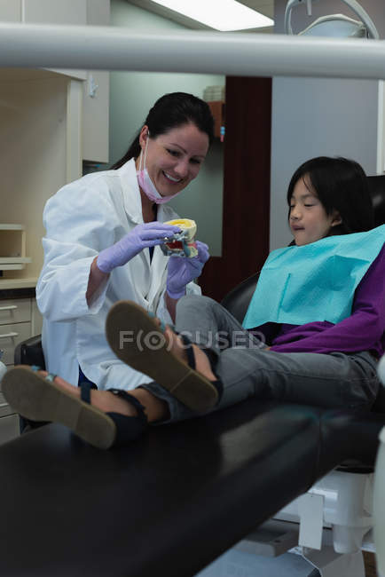 Female dentist explaining about teeth model in clinic — Stock Photo