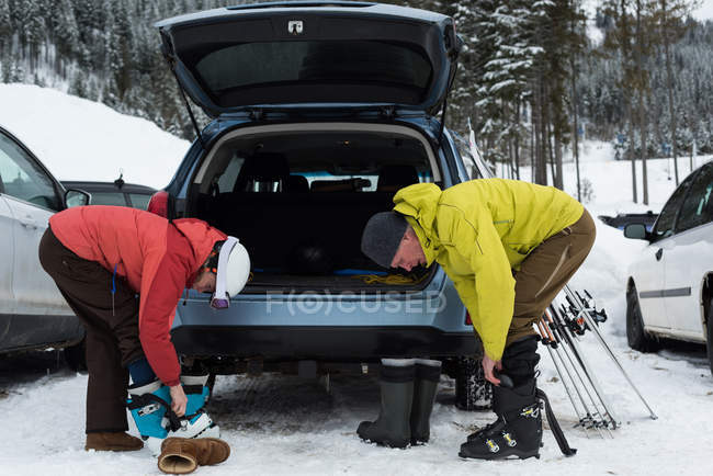 Seniorenpaar trägt Skischuh neben Auto — Stockfoto