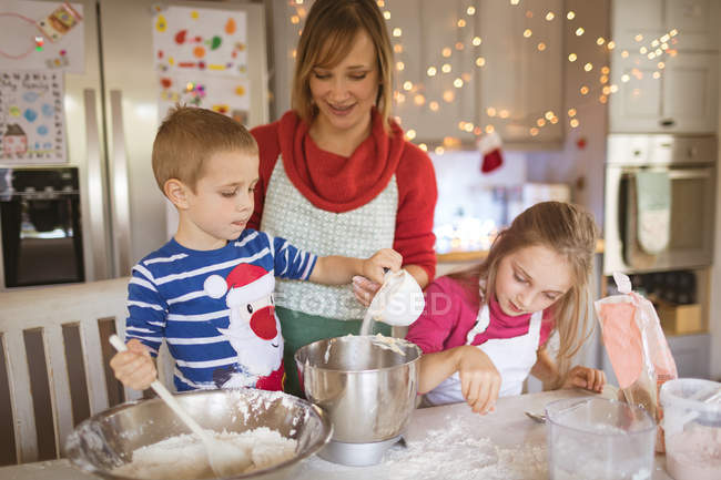 Mother and kids preparing dough to make Christmas cookies at home — Stock Photo