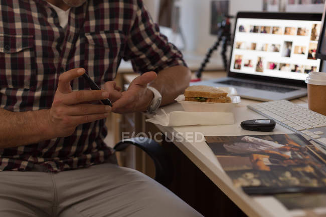 Mid section of businessman checking blood sugar with glucometer in office — Stock Photo