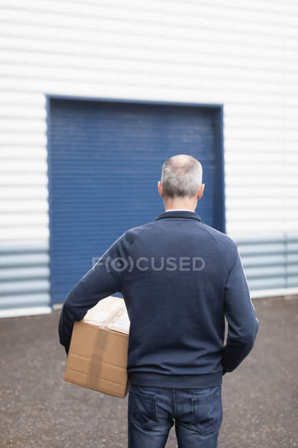 Vista posteriore del fattorino che trasporta il pacco al magazzino — Foto stock