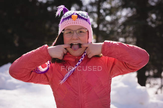 Menina puxando rostos engraçados durante o inverno em um dia ensolarado — Fotografia de Stock