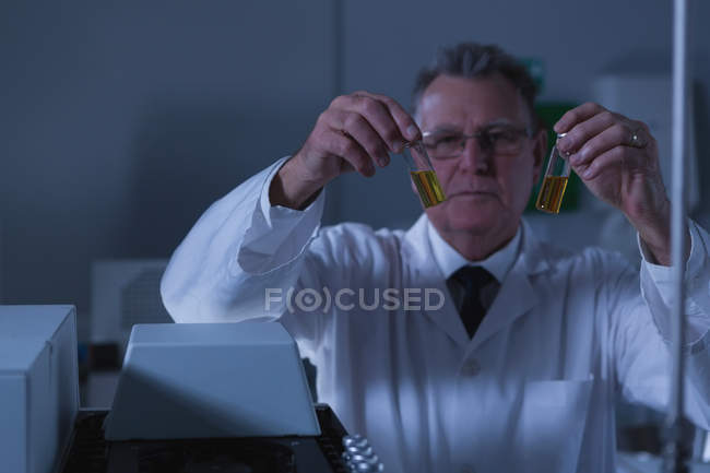 Male scientist placing medical vials on a lab machine in laboratory — Stock Photo
