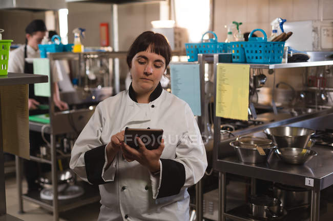 Женщина шеф-повар с помощью цифрового планшета на кухне в ресторане — стоковое фото