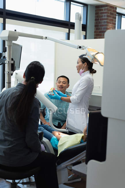 Dentiste féminine expliquant le modèle de dents en clinique — Photo de stock