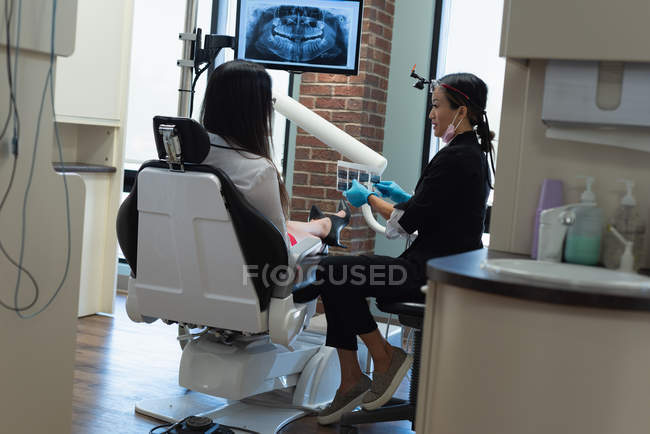 Une dentiste interagit avec un patient en clinique dentaire — Photo de stock
