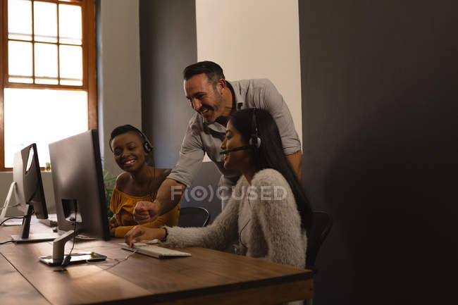 Happy business colleagues discussing over a computer in office — Stock Photo