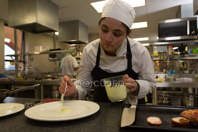 Шеф-повар, подающий соус на тарелке в ресторане — стоковое фото