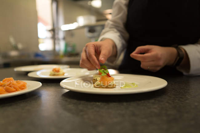 Close-ip des Küchenchefs garniert Essen auf dem Teller — Stockfoto