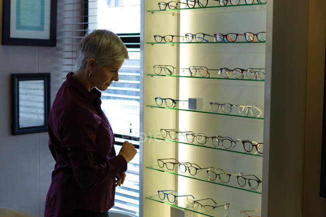 Femme âgée sélectionnant le cadre dans la clinique — Photo de stock