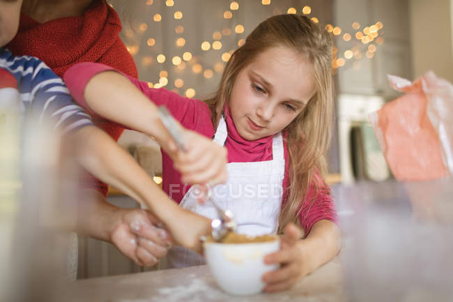 Fille mélangeant les ingrédients dans la tasse à la maison — Photo de stock