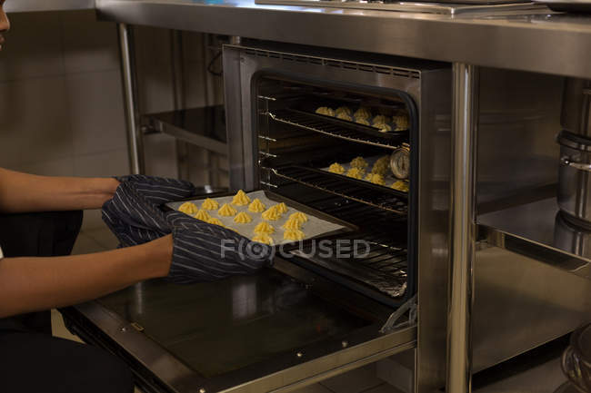 Koch legt Blech mit Keksen in Backofen im Restaurant — Stockfoto